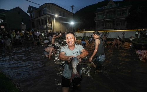 Du khách tham gia sự kiện bắt cá tại một ngôi làng ở Hàng Châu. Ảnh: Xinhua