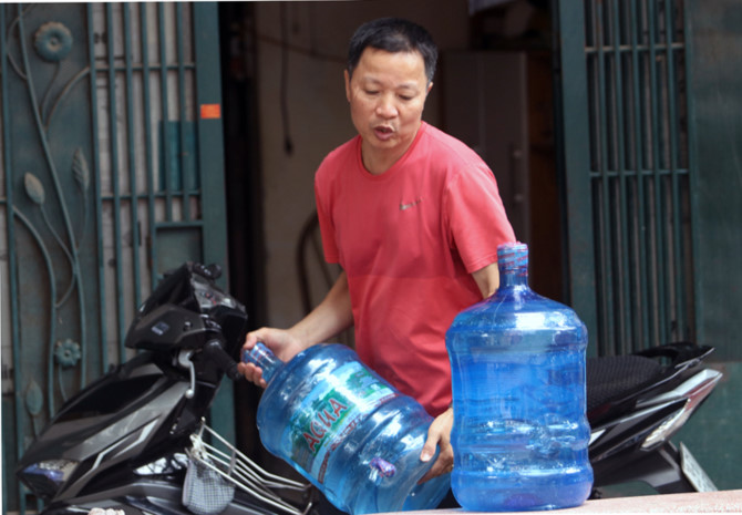 Nước đóng bình được chuyển đến nhà người dân ở Khương Đình, Thanh Xuân. Ảnh: Võ Hải.